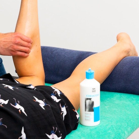 Fles CHEMODOL massageolie naast een vrouw die een beenmassage krijgt.