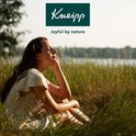 Vrouw met gesloten ogen in het gras, genietend van de natuur. Kneipp logo erboven.