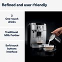 Melk wordt opgeschuimd en in een kopje geschonken door een hand met een melkopschuimer, naast de zilveren De'Longhi Magnifica S espressomachine.