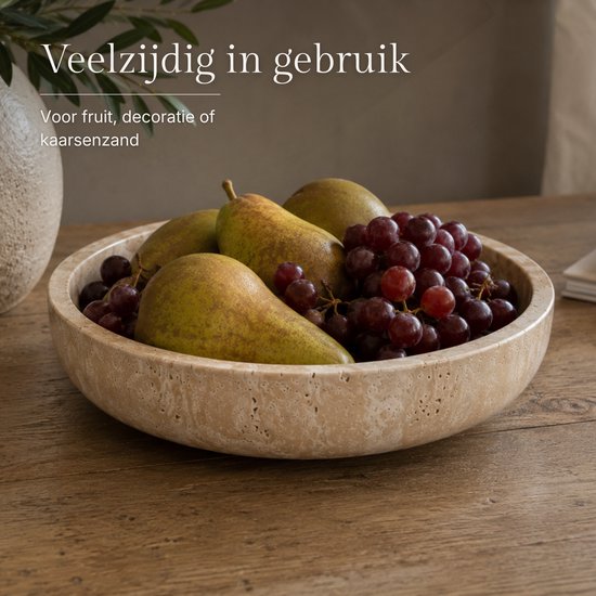 Beige travertin schaal gevuld met peren en druiven.