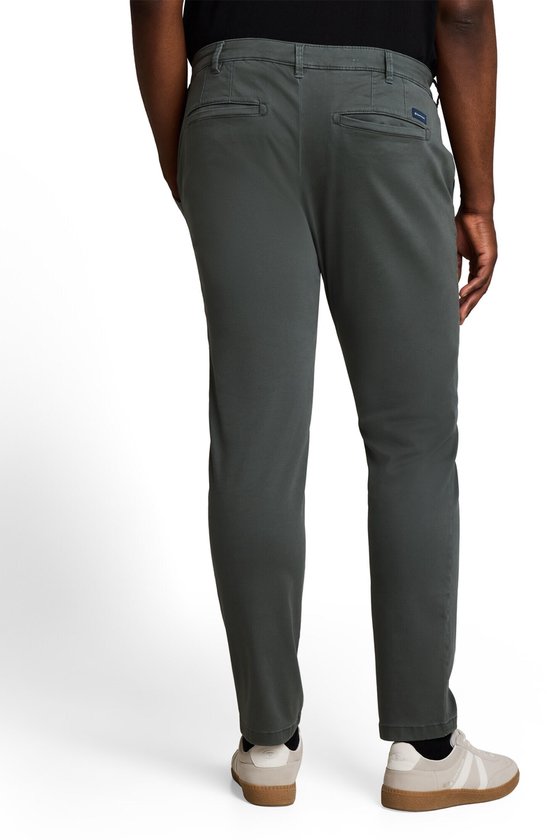 Donkere olijfgroene chino, normale pasvorm, met achterzakken. Gedragen door een model.