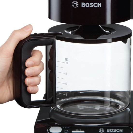 Hand die een zwarte Bosch koffiemachine pakt bij de zwarte handgreep van de glazen kan.