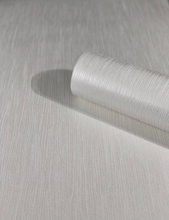 Een rol zilverwit vliesbehang met een fijne, verticale zandkorrel structuur, deels afgerold.