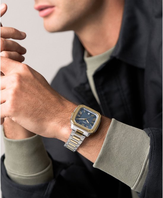 Herenhorloge met zilverkleurige en gouden schakelband, goudkleurige kast en blauw met Romeinse cijfers.