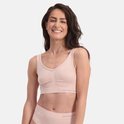 Een lachende vrouw in een lichtroze naadloze BH van Bamboo Basics. De BH heeft een V-hals en ruches in het midden.