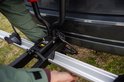 Detailopname van de bevestiging van een trekhaakfietsendrager aan een auto, met kabelaansluitingen.