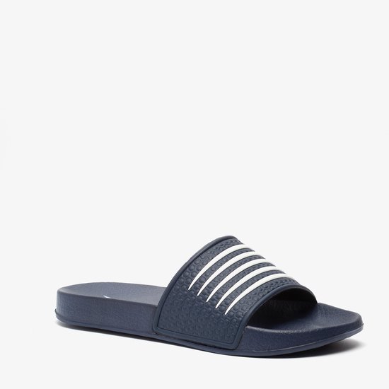 Donkerblauwe slipper met witte strepen op de band, in een schuine positie.
