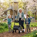 Oudere vrouw met rollator loopt met kleinkinderen in een park