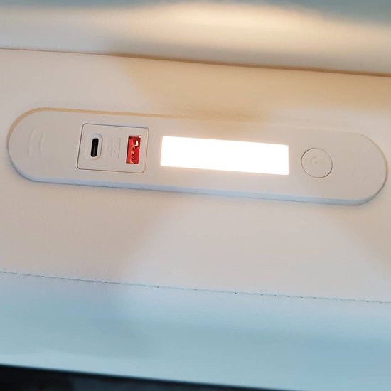 Detail van een ingebouwd verlichtingspaneel met USB-C poort en aan/uit-schakelaar op een wit bed.