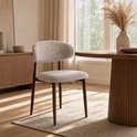 Stoel met taupe stoffen zitting en rugleuning en bruine houten poten, in een woonkamer.