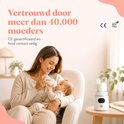 Moeder met baby op schoot in een stoel, geeft flesje melk. Naast een witte flesverwarmer. "Vertrouwd door meer dan 40.000 moeders". CE en BPA-vrij logo's zichtbaar.