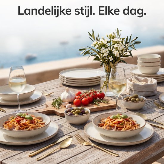 Tafel gedekt voor 12 personen met beige servies. Pasta wordt geserveerd op borden en in kommen, met wijnglazen en olijven.