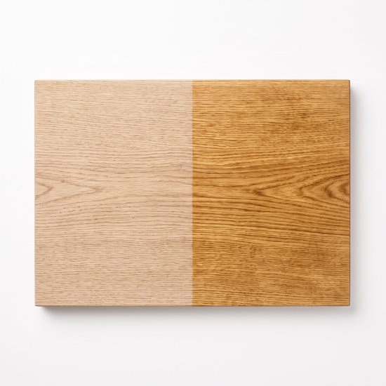 Houten snijplank met een helft onbehandeld en de andere helft behandeld met olie.