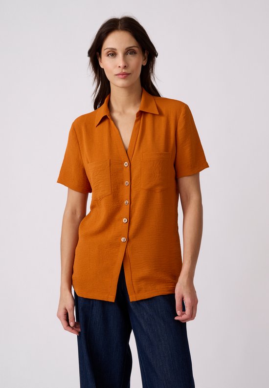 Oranje blouse met korte mouwen, twee borstzakjes en knoopsluiting. Gemaakt van crêpestof met kreukeffect.