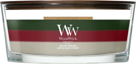 WoodWick Trilogy kaars met drie lagen: groen, rood en wit, in een glazen pot, op zwarte achtergrond.