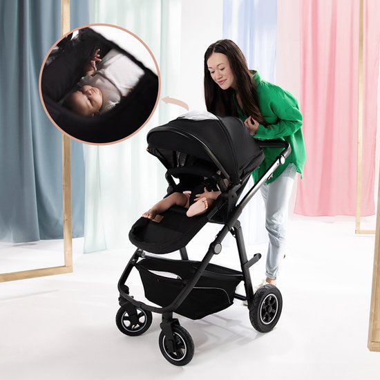 Grijze kinderwagen met baby erin, een vrouw duwt de kinderwagen.