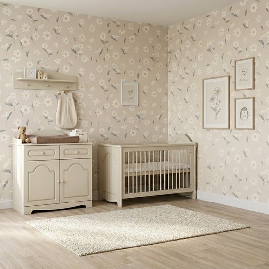 Babykamer met crèmekleurig ledikant, commode, zachte vloer en bloemetjesbehang.