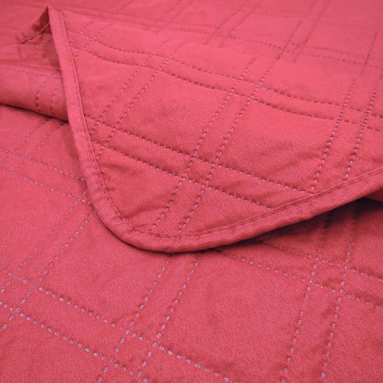Rood doorgestikt sprei met ruitpatroon.