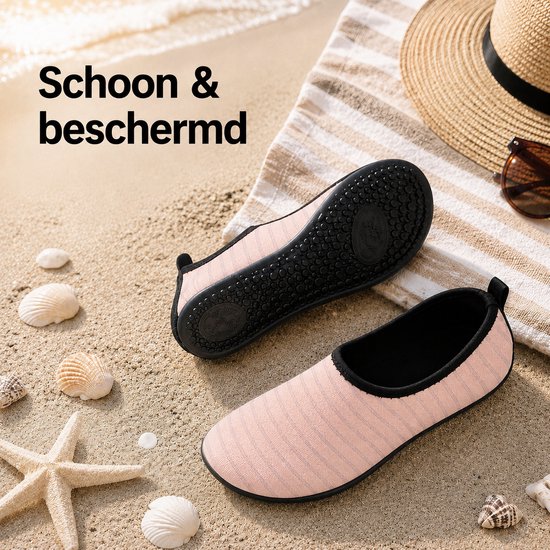 Roze gestreepte waterschoenen, één met zool omhoog, op zand met schelpen en zonnehoed.