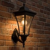 Zwarte klassieke wandlamp op een bakstenen muur, gloeiend met warm licht.
