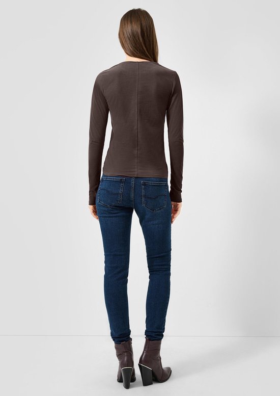 Achterkant: Vrouw met donkerbruine longsleeve, blauwe jeans en enkellaarsjes.