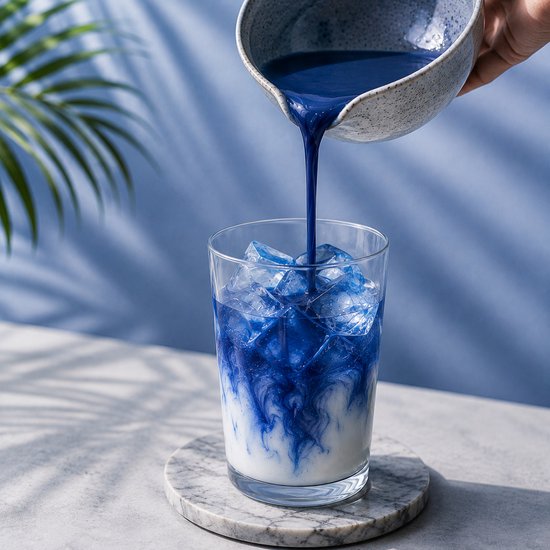 Blauw Blue Matcha drankje dat in een glas met ijsblokjes wordt geschonken. Mooi marmerpatroon van melk en drank.