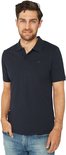 Man in donkerblauw poloshirt en spijkerbroek, handen in de zakken.