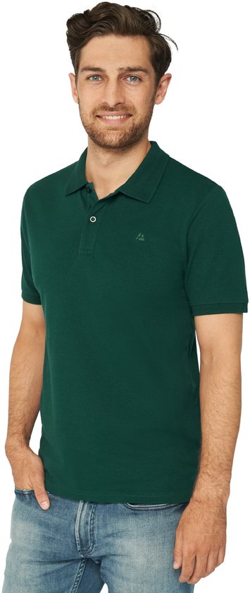 Man met een glimlach in een donkergroen poloshirt met korte mouwen en spijkerbroek.