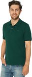 Man met een glimlach in een donkergroen poloshirt met korte mouwen en spijkerbroek.
