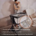 Lit cododo gris avec une femme tenant son bébé. Le panier de rangement en dessous est rempli de jouets et d'accessoires.