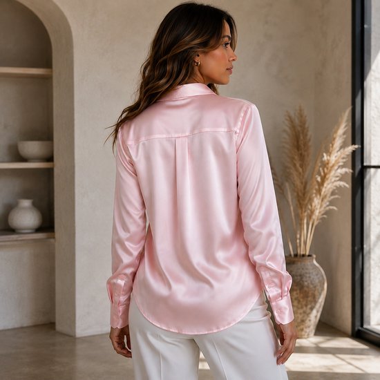 Achterkant van een roze satijnen blouse met lange mouwen, gedragen door een model met witte broek.