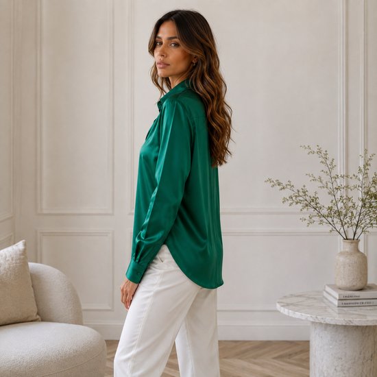 Model draagt een smaragdgroene satijnen blouse met lange mouwen, van achteren gezien.