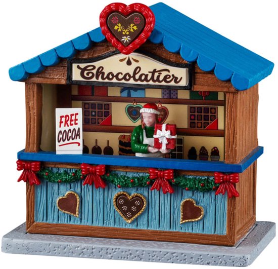 Chocolatier kraam met blauw dak, houten wanden, versierd met kerstgroen en strikken. Een figuur met cadeautje. Tekst 'FREE COCOA'.