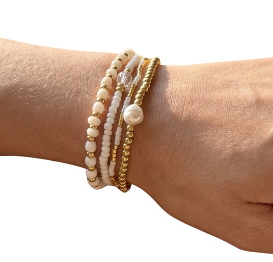Set van vier gouden en witte kralenarmbanden, waarvan één met parel.