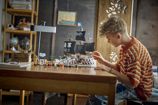Jongen bouwt aan de LEGO Garp's Marine Battleship op een houten tafel.