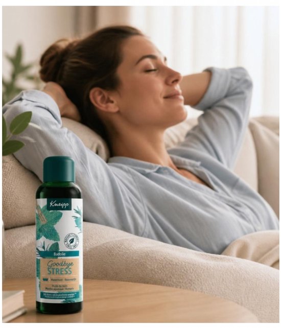 Vrouw met ogen gesloten op een bank met fles Kneipp Goodbye Stress badolie met watermunt en rozemarijn.