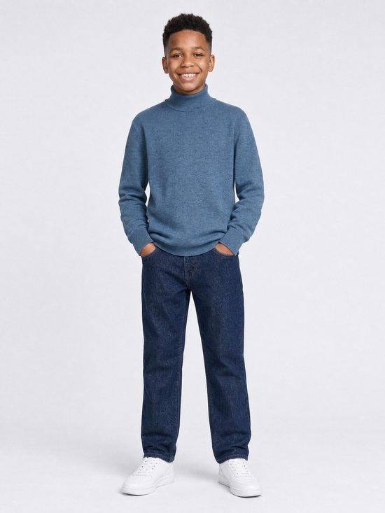 Jongen in Petrol Industries blauwe fijngebreide coltrui met donkerblauwe jeans en witte sneakers.