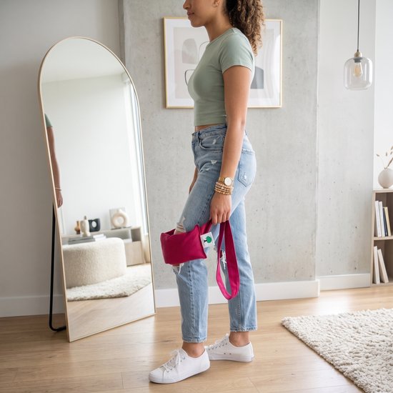 Vrouw met groene top en spijkerbroek houdt een roze warmtekussen vast.