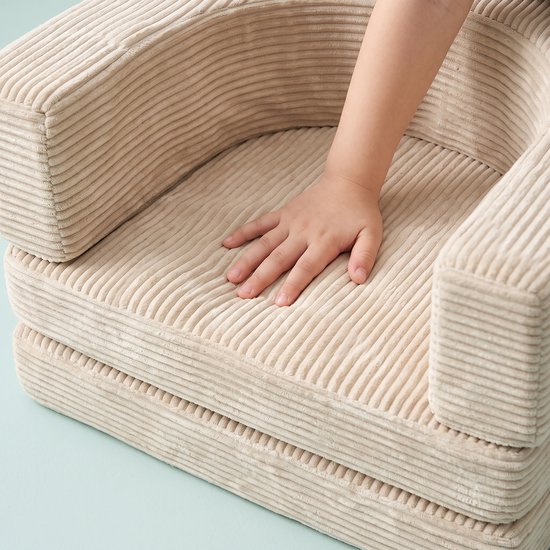 Een kinderhand rust op een beige corduroy speelbankje.