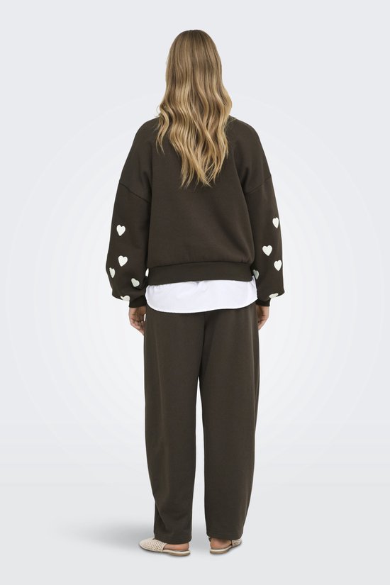 Achterkant van een donkerbruine sweater met witte hartjes op de mouwen, gedragen door een model.