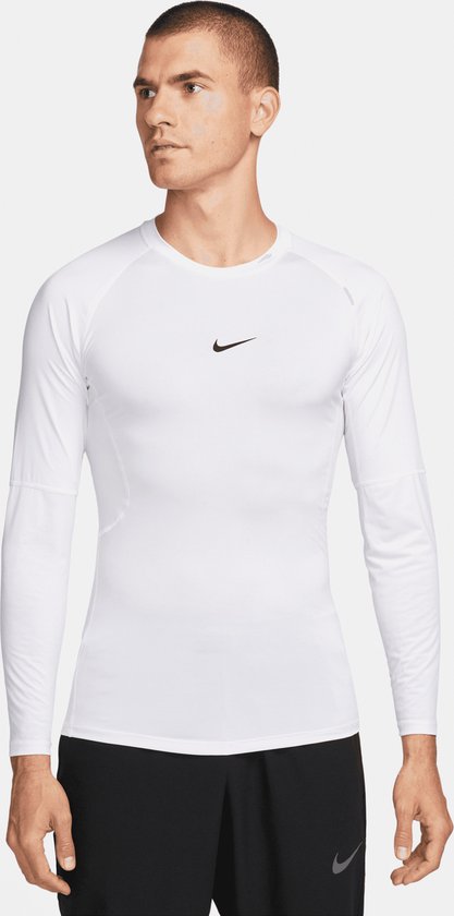 Man draagt wit Nike Pro longsleeve shirt met zwart Nike logo op de borst en zwarte shorts.