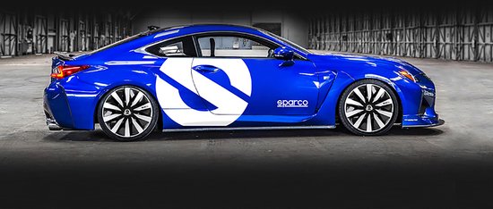 Een glimmende blauwe sportwagen met een grote witte Sparco 'S' op het portier en zwarte wieldoppen.