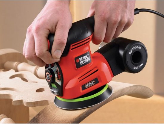 Handen gebruiken een oranje en zwarte BLACK+DECKER multischuurmachine op een gebogen houten oppervlak.