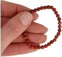 Een rood jaspis kinderarmbandje van 4 mm, met kralen, vastgehouden in een hand.