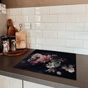 Protection d'induction avec imprimé floral sur un comptoir sombre avec des carreaux blancs.