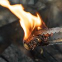 Tang houdt een brandende aanmaakwokkels met veel vlammen.