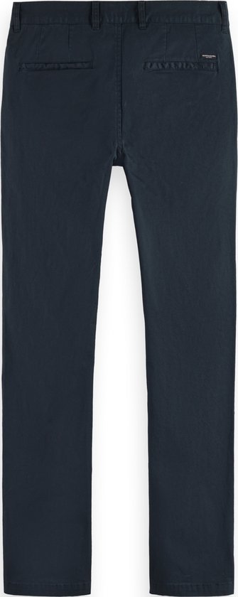Achterkant van donkerblauwe chino met twee achterzakken en een klein label rechts.