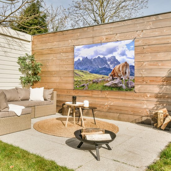 Banner met koe en bergen, hangend aan een houten wand op een terras.