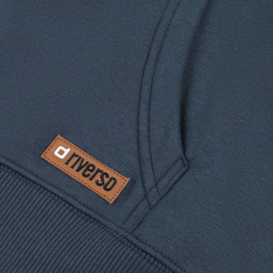 Detail van een bruin logo-label met 'riverso' op een donkerblauwe hoodie.