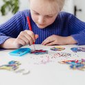 Enfant avec pull bleu faisant de la peinture diamant sur une figurine de Stitch.